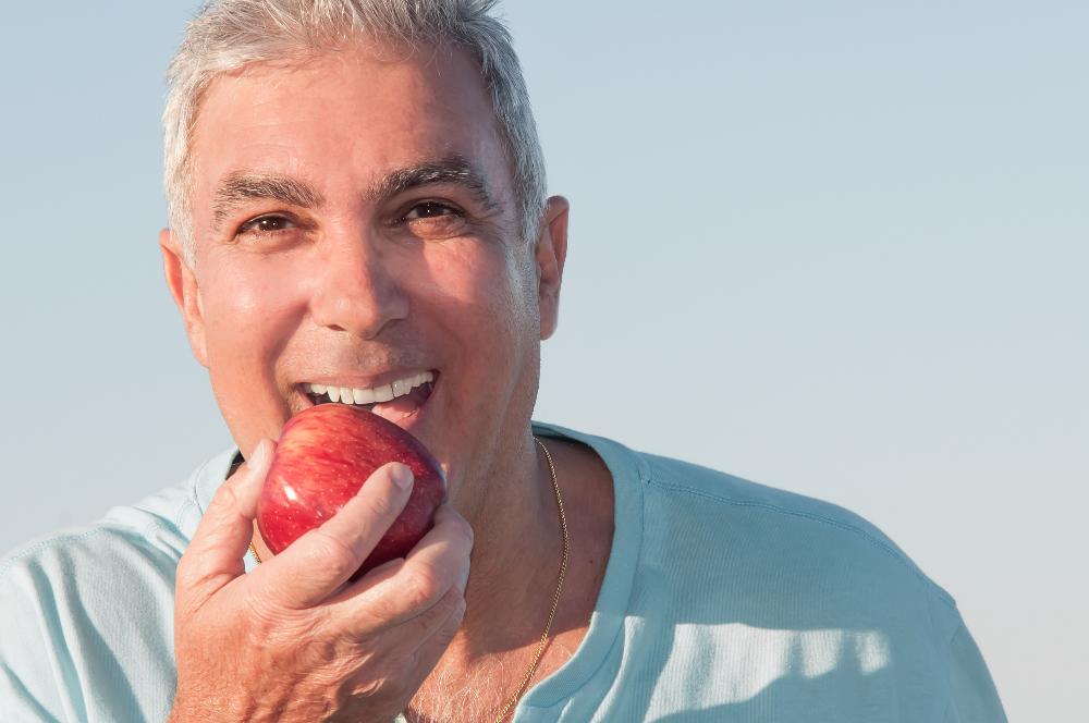 A man eating an apple | dental plans Chesterfield Missouri
