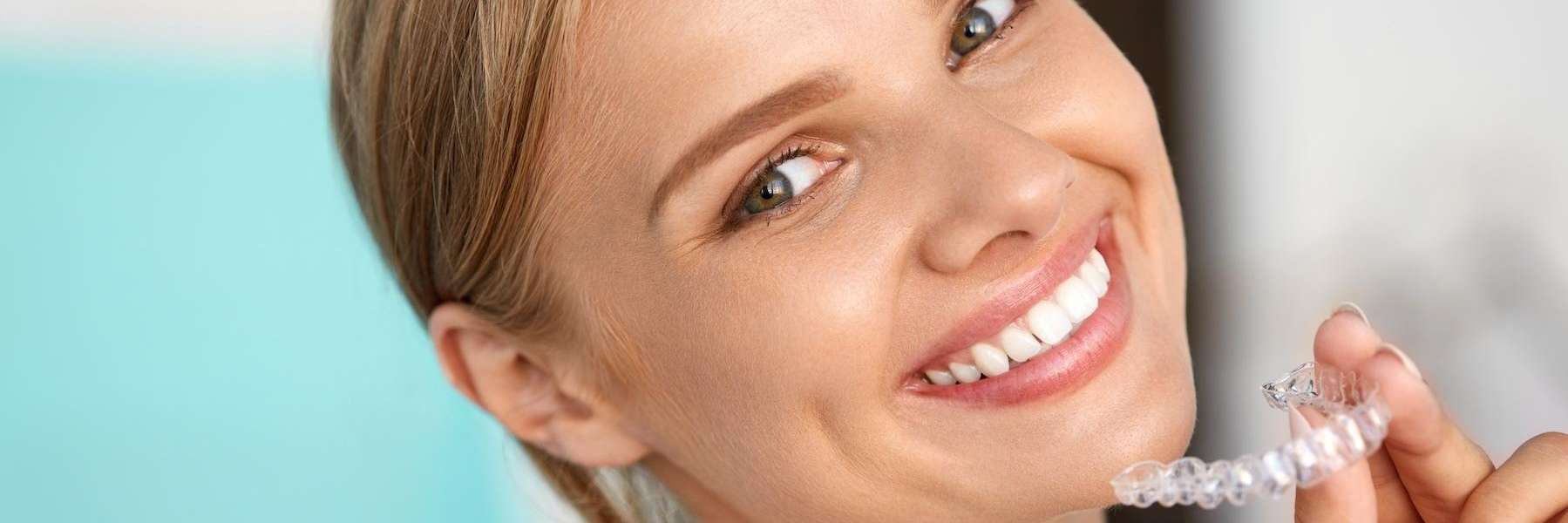 A smiling woman holding an Invisalign tray
