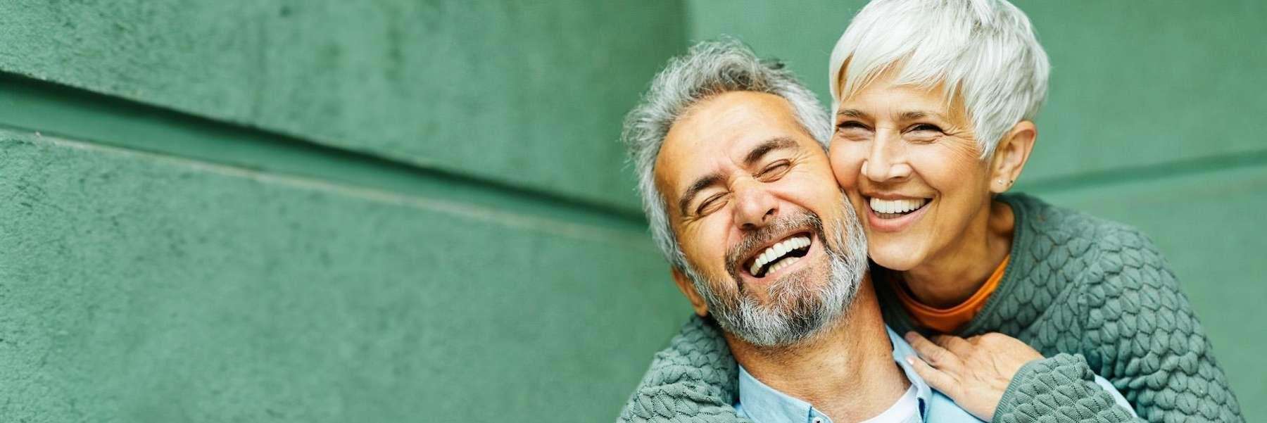 A smiling couple against a green background